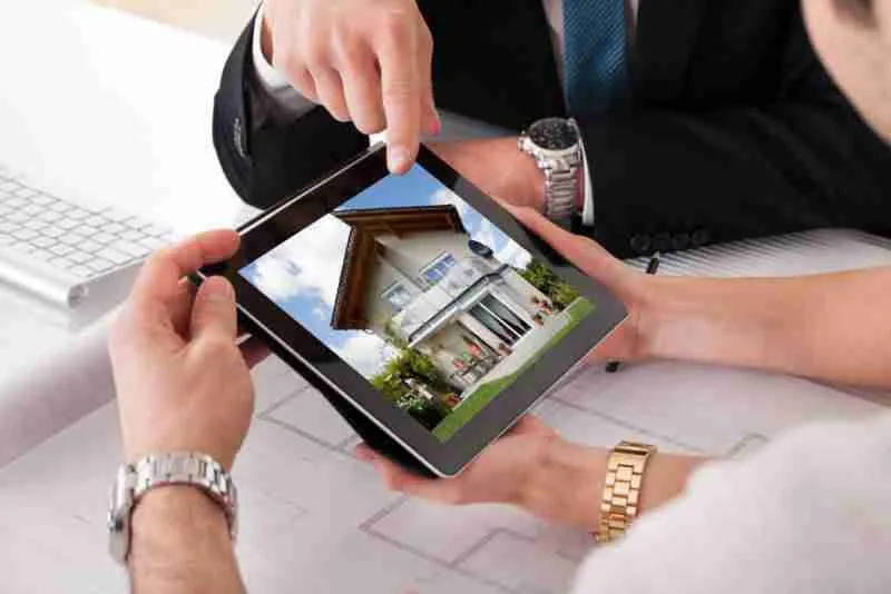 Imprenditore che analizza un modello di casa su tablet.